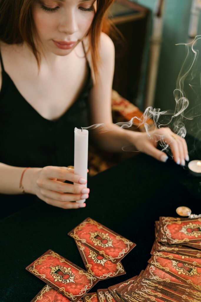 Vela encendida junto a un mazo de tarot sobre paño negro